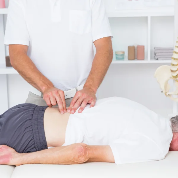 Un homme reçoit un massage du dos par un kinésithérapeute pour soulager ses douleurs lombaires.