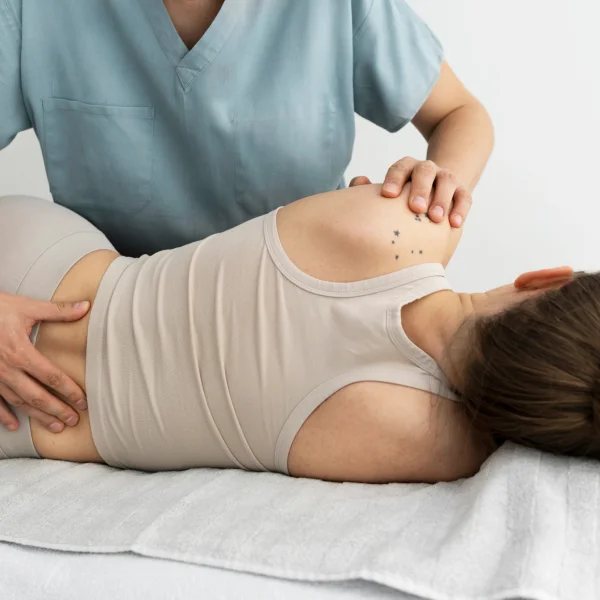 Une femme reçoit un massage du dos par un médecin pour soulager ses douleurs lombaires.
